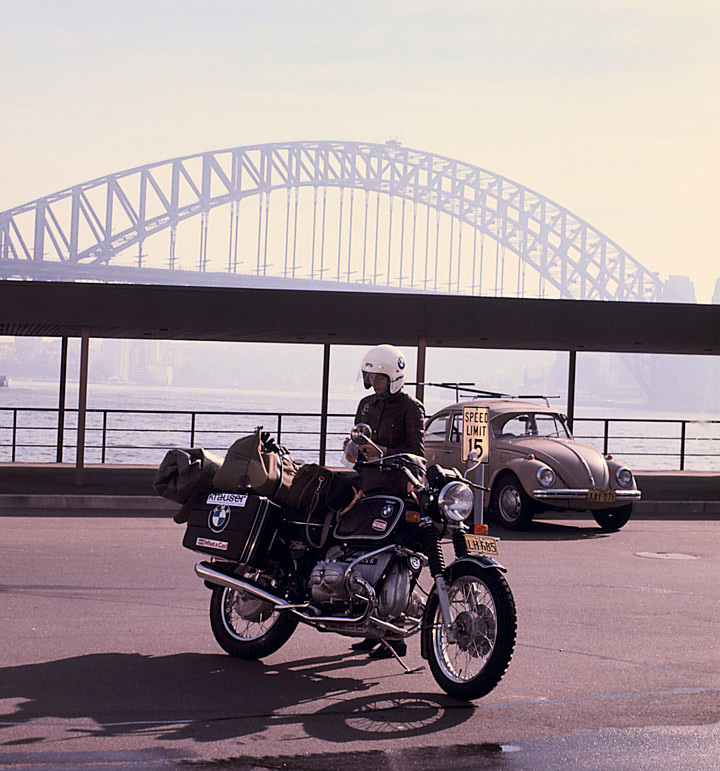 femme a cote de sa moto avec un pont en fond